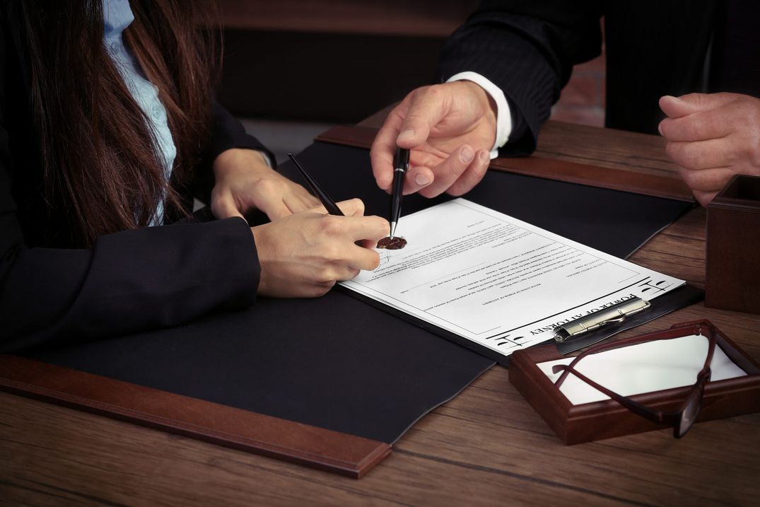 A signer completing a Power of Attorney document at a desk while a notary guides the signing