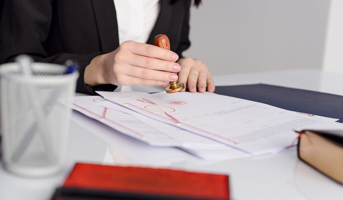 A notary applying a seal to official documents on a desk